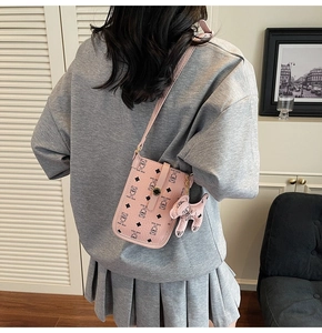 Pink crossbody phone bag with teddy bear print and cute dog charm shown on a model