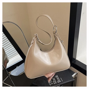Detail of beige crescent underarm bag with silver rings and leather texture