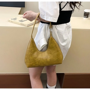 Detail of yellow crocodile embossed texture on a crescent shoulder bag with metal zipper