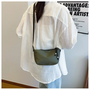 Olive green crescent shoulder bag shown on model with adjustable black strap and woven puller