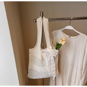 Détail du sac cabas en maille ajourée avec nœuds en dentelle blanche et style estival