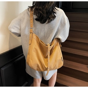 Model view of large mustard canvas tote bag with adjustable strap and metal eyelets