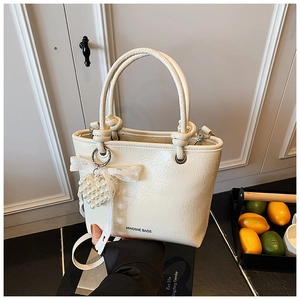 Detail of cream pleated tote bag with pearl heart charm and lace bow decoration