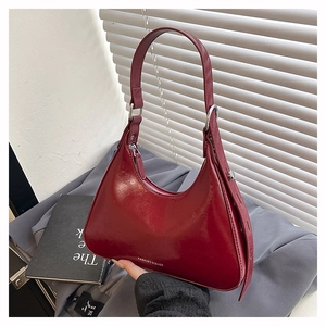 Detail of burgundy underarm bag with glossy finish and silver ring strap adjustment