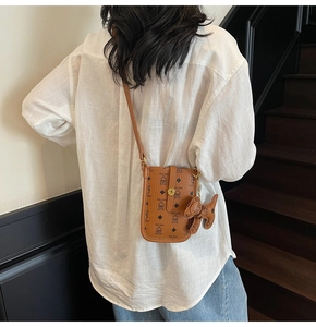 Rear view of a model wearing the brown leather crossbody phone bag with logo patterns