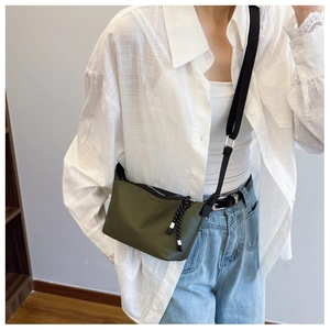 Detail of army green nylon crossbody bag showing durable texture and zip puller