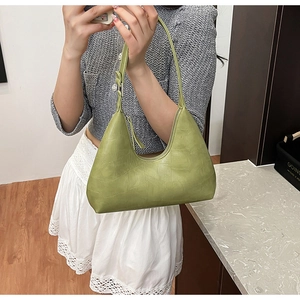 Detail of light green crescent underarm bag featuring a textured crocodile skin pattern