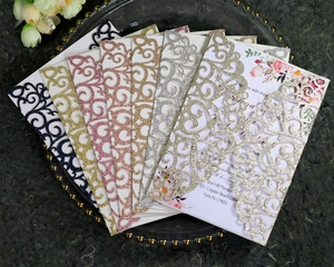 Close-up of glittery laser-cut wedding invitations in multiple colors on a decorative plate