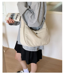 Détail d'un sac hobo en nylon beige avec boucle métallique ronde et design moderne