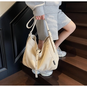 Close-up of adjustable wide shoulder strap with silver eyelets on a cream canvas hobo bag