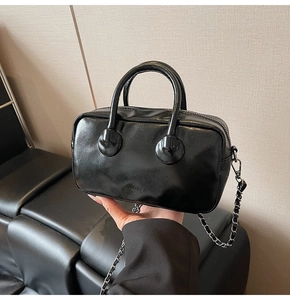 Detail of glossy black leather bowling bag with silver chain strap and top handles