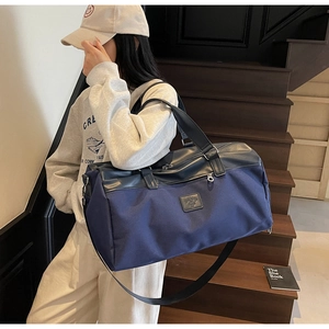 Detail of blue canvas travel bag with leather handles and detachable strap on stairs