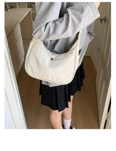 Détail d'un sac demi-lune en nylon crème avec poche latérale et boucle métallique chic