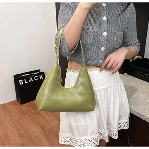 Chic green crocodile embossed hobo bag worn on shoulder by model in a casual indoor setting