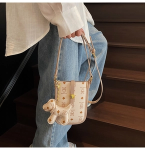 Detail of light beige leather phone crossbody bag with teddy bear pattern and dog charm