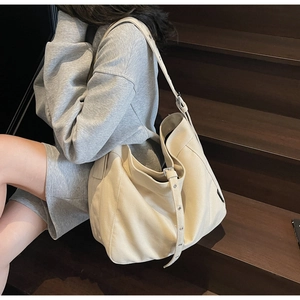 Detail of beige canvas tote bag with adjustable metal eyelet shoulder strap on model
