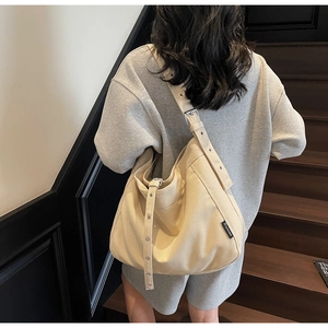Detail of adjustable strap with metal buckles on beige canvas hobo shoulder bag