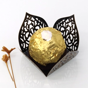 Macro detail of laser-cut black cardstock chocolate wrapper with floral vine patterns