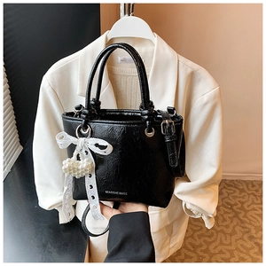 Detail of black wrinkled PU leather bucket bag with lace bow and pearl heart charm