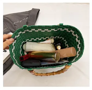 Vue de dessus du sac seau tressé vert avec poignées en bambou et accessoires du quotidien