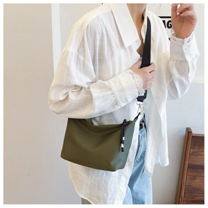 Close-up of olive green nylon dumpling bag with adjustable strap and braided zipper pull
