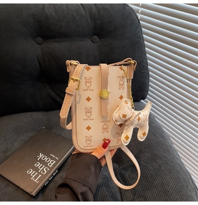 Detail of off-white leather phone bag with cartoon bear print and puppy charm