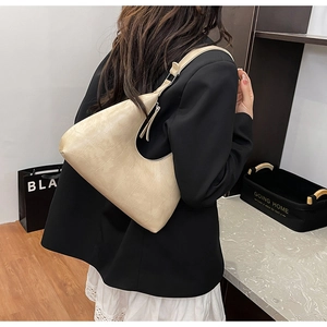 Detail view of beige croc-embossed hobo bag worn on shoulder for stylish outfit