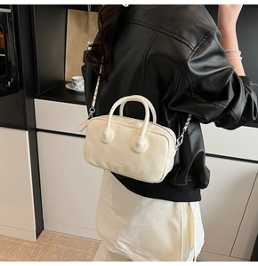 Creamy white bowling bag featuring a silver chain strap and modern brand logo detail