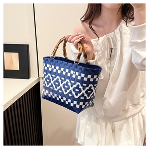 Détail du sac cabas tissé bleu et blanc avec poignée en bambou et anneaux dorés