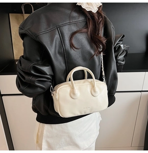 Close-up of cream mini bowling bag with silver chain strap and CLEAR UX logo detail