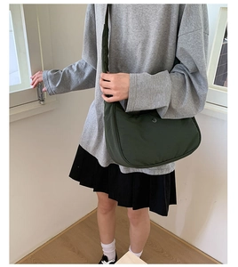 Vue détaillée du sac en nylon vert foncé en forme de croissant avec un logo en métal rond
