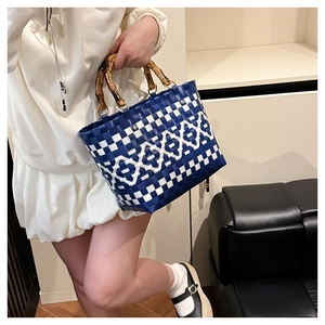 Détail du sac tissé bleu et blanc avec poignées en bambou naturel et anneaux en métal