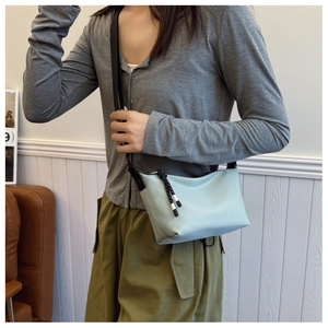 Close-up of light blue crossbody bag with black and white woven drawstring detail