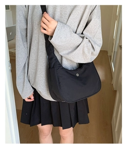 Détail d'un sac demi-lune en nylon noir avec bandoulière ajustable sur une femme