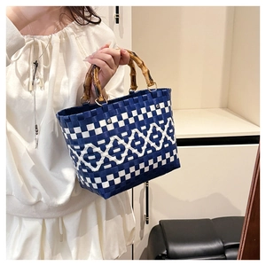 Détail du sac cabas tressé bleu et blanc avec poignées en bambou et motifs géométriques