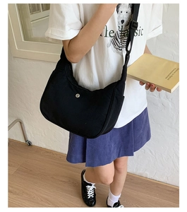 Détail du sac demi-lune en nylon noir avec bandoulière réglable porté par un modèle