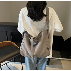 Detail view of grey canvas tote bag with adjustable eyelet strap and side logo tag