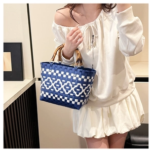 Détail du sac cabas tissé avec motifs géométriques bleus et poignées en bambou naturel