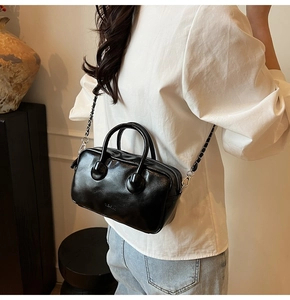 Detail of black glossy bowling bag with chain strap shown in a lifestyle home setting
