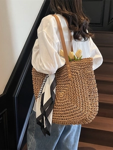Large capacity straw tote bag with brown leather straps and striped scarf on stairs