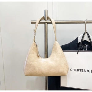 Detail of beige hobo bag featuring premium crocodile embossed texture and silver zipper