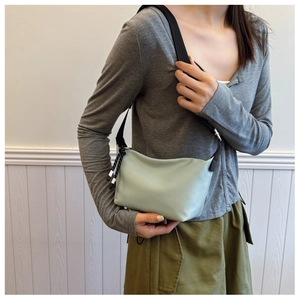 Macro view of mint green dumpling bag with contrast drawstring and black woven strap