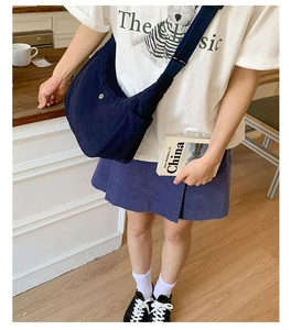 Détail d'un sac demi-lune en nylon bleu marine avec logo doré et bandoulière réglable