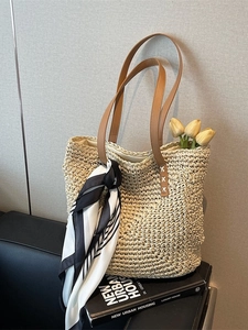 Beige woven straw tote bag with brown leather handles and striped scarf decoration