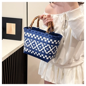 Détail du sac seau tissé bleu et blanc avec poignées en bambou dans un décor d'intérieur