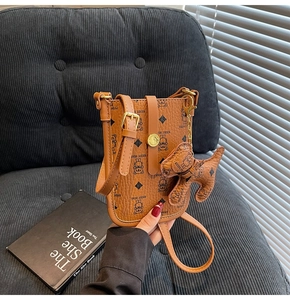 Close-up of brown pebbled leather phone bag with bear print and dog-shaped charm detail