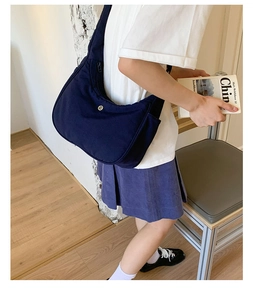Détail du sac croissant en nylon bleu foncé montrant le logo en métal et le tissu
