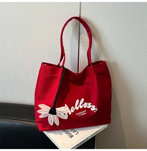 Detail of red canvas tote bag with white text print and decorative mesh daisy charm