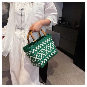 Détail d'un sac cabas tissé vert et blanc avec une poignée en bambou naturel