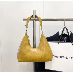 Detail of mustard yellow hobo bag featuring crocodile embossed texture and adjustable strap
